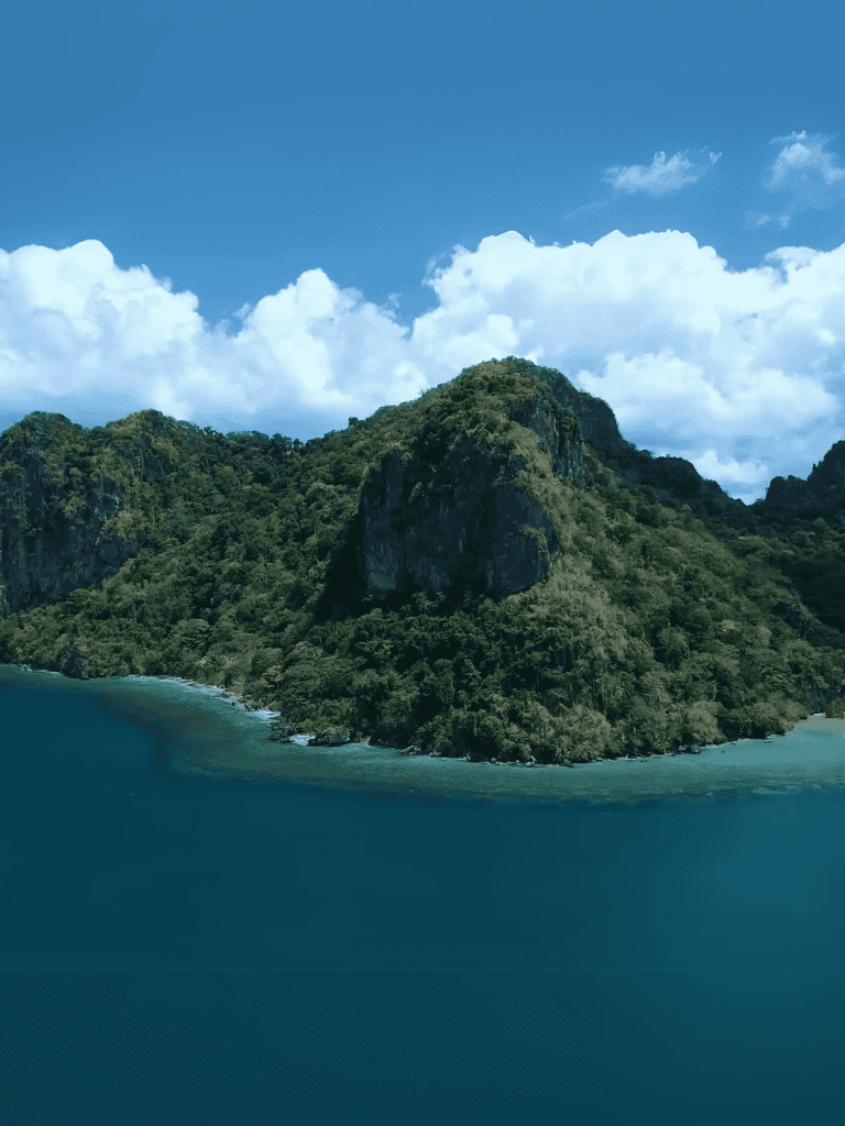 Famous tropical island covered in lush green jungle surrounded by blue ocean waters with a clear sky.