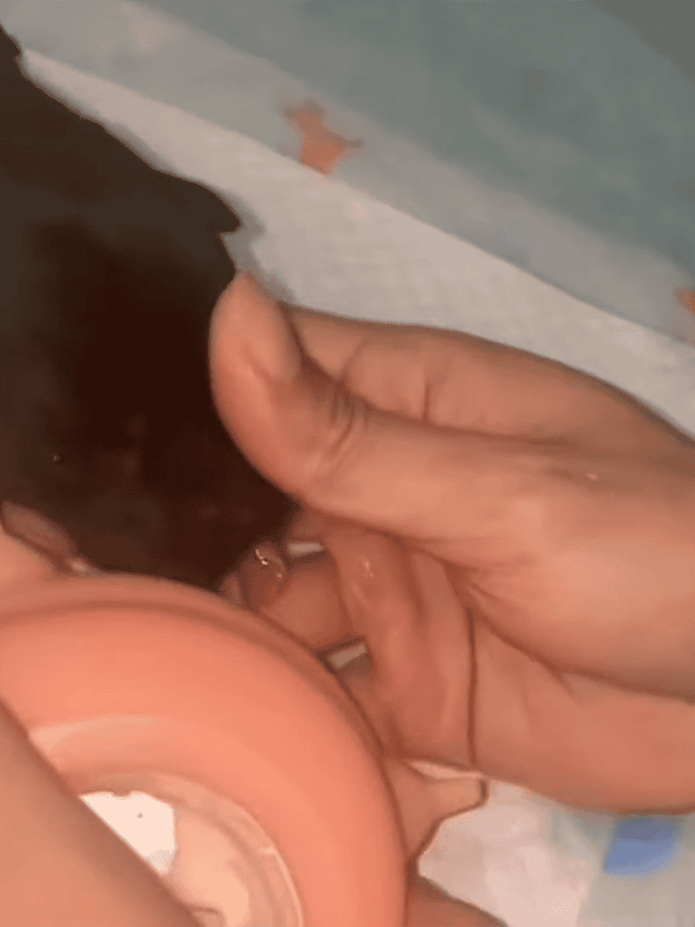 Alt text: Close-up of a person breastfeeding a tiny puppy with care.