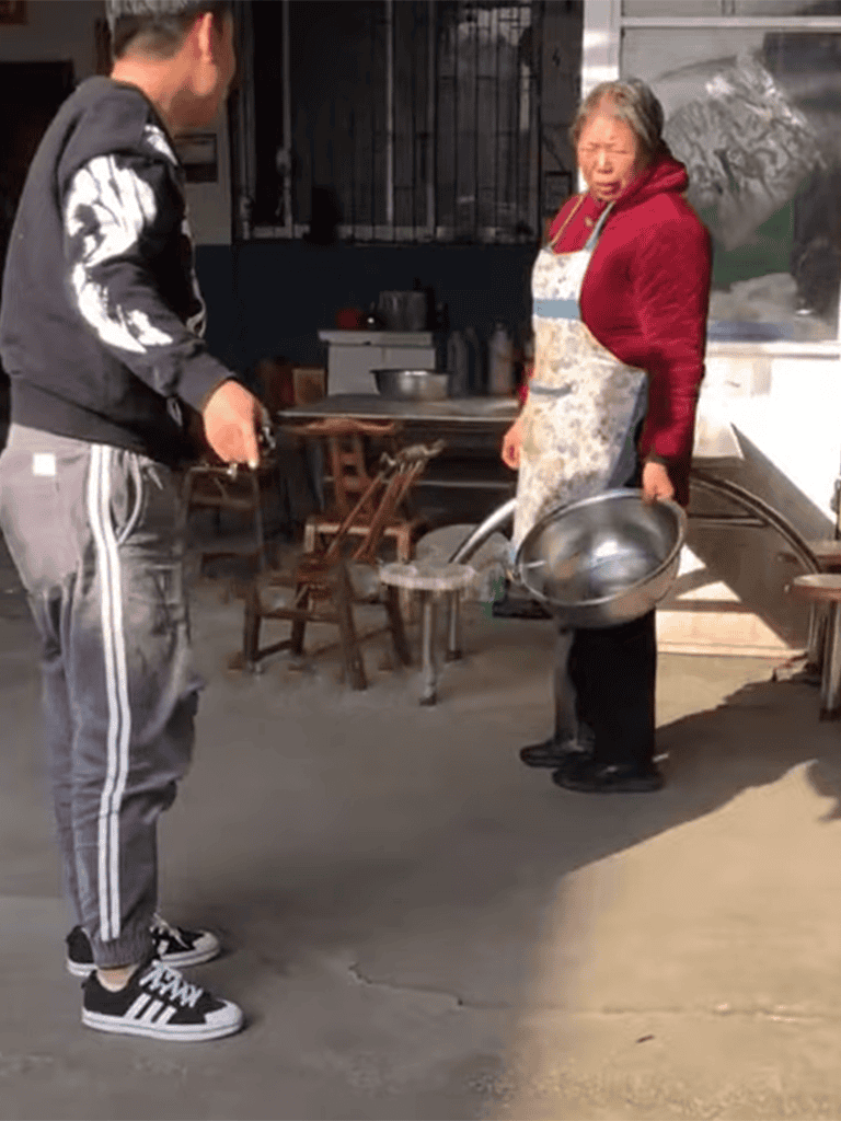 A gentleman helping a stray dog find shelter outside a rustic home.